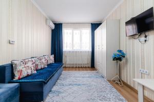 een woonkamer met een blauwe bank en een tv bij Жилой Комплекс Акварель in Alma-Ata