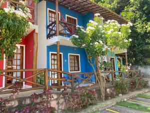 una casa azul y blanca con árboles y flores en Apartamento em Lençóis, Cond. Vivendas do Serrano 105 en Lençóis