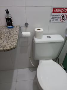a white toilet in a bathroom with a sign on the wall at Vivendas do Serrano Apart105 Lençois in Lençóis