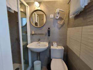 a bathroom with a sink and a toilet and a mirror at The Originals Access, Hotel Le Canter Saumur in Saumur