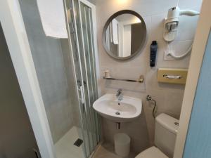 een kleine badkamer met een wastafel en een spiegel bij The Originals Access, Hotel Le Canter Saumur in Saumur