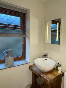 a bathroom with a white sink and a window at Hollies Cottage in Keighley