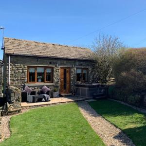 a small stone house with a lawn in front of it at Hollies Cottage in Keighley