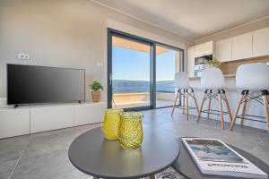 a living room with a tv and a table and chairs at Mare‘s Place - Premium Seaview Apartment in Slatine