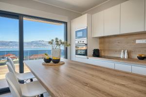 a kitchen with a wooden table and a large window at Mare‘s Place - Premium Seaview Apartment in Slatine