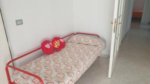 un letto con due cuscini rossi sopra di Apolloni di Loano appartamento privato - Codici Citra visibili su STRUTTURA a Loano
