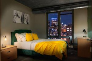 ein Schlafzimmer mit einem Bett mit gelber Bettwäsche und einem Fenster in der Unterkunft Affordable 2-Bedroom on Wabash in Chicago