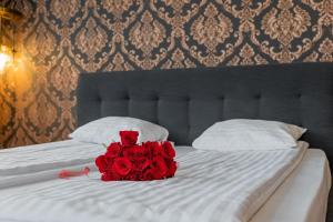 オラデアにあるApartamente La Teatru Orientのベッドに座る赤いバラの花束 +5枚の写真