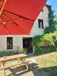 a picnic table under a red umbrella in front of a house at la maison sous le château in Montségur
