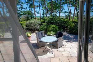 d'une terrasse avec une table et des chaises en verre. dans l'établissement Strandhotel Fontana, à Timmendorfer Strand