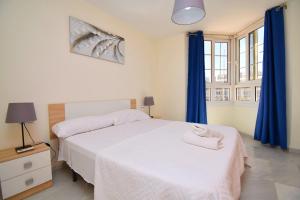 1 dormitorio con cama blanca y cortinas azules en Expoholidays - Apartamentos Puerto Almerimar en Almerimar