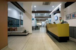 a man standing at a counter in a lobby at Slim Pajuçara by Tropicalis in Maceió