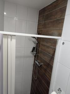 a bathroom with a shower with a wooden wall at Apartmány Skala in Příbram