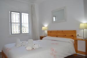 a bedroom with two beds with white sheets and two windows at Casa Mar i Sol in L'Ampolla