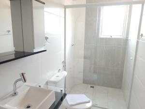 a white bathroom with a sink and a toilet at Verissimu's Pousada in Paraisópolis