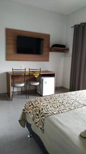 a bedroom with a bed and a desk and a tv at Hotel Central in Boa Esperança