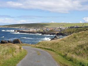 a dirt road next to the ocean on a hill at Old Police Station, Portsoy in Portsoy