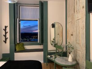 a room with a window with a table and a mirror at Ilha 12 Suites in Coimbra
