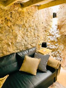 un sofá de cuero negro en una habitación con una pared de piedra en La Ruta - La Cueva, en Confrides
