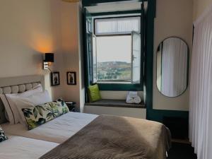 a bedroom with a bed and a window with a mirror at Ilha 12 Suites in Coimbra