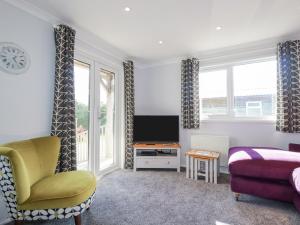 a bedroom with a bed and a tv and a chair at Lowena in Saint Day