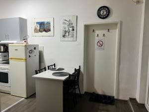 cocina con nevera, mesa y reloj en Hardy's Apartment, en Belgrado