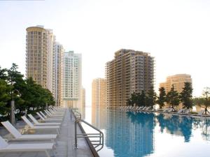 a row of white lounge chairs next to a body of water at Wonderful 2/2 Condo at Icon Brickell With Pool in Miami