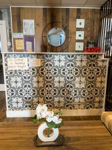 a room with a wall with a mirror and a vase with flowers at 7 Day's Hotel in Lamont