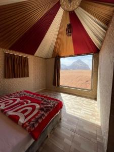 a bed in a room with a view of the desert at Panorama camp jeep trips in Wadi Rum