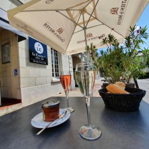 a table with two glasses of wine and a basket of bread at The Originals Access, Hotel Le Canter Saumur in Saumur