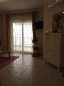 a living room with a dresser and a large window at Seaflows Apartments #3 in Paralia Katerinis