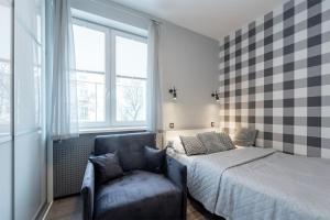 a bedroom with a bed and a chair and windows at HILLWOOD Apartment in Łódź