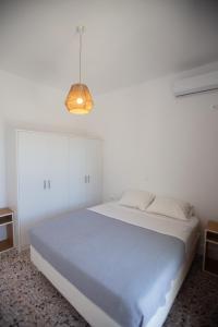 a white bedroom with a large bed and a light fixture at TIKI BEACH STUDIOS in Nea Makri