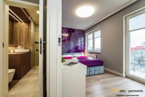 a bedroom with a purple bed and a bathroom at Baltic Apartments - Apartamenty Bałtyk in Świnoujście