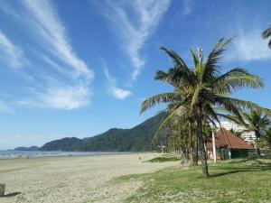 a beach with two palm trees and a house at "Nossa Casa Da Praia" Peruíbe SP in Peruíbe