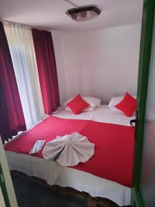 a bedroom with a red and white bed with red pillows at Cabana in poiana padurii in Recaş