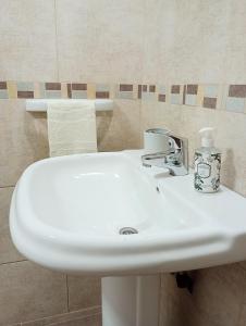 - un lavabo blanc dans la salle de bains avec une bouteille de savon dans l'établissement La Casita, à Esquel