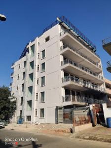 a tall white apartment building on the side of a street at Dev Residency in Gurgaon