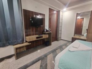 グルガオンにあるDev Residencyのベッド1台、薄型テレビが備わるホテルルームです。