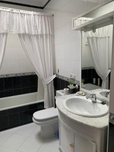 a white bathroom with a sink and a toilet at Al ladito de Sevilla in Bormujos
