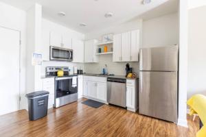 a kitchen with white cabinets and a stainless steel refrigerator at Modern Upscale 1BR Fountain Square in Indianapolis