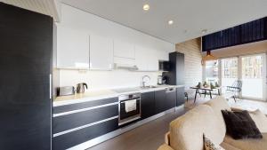 eine Küche mit schwarzen und weißen Schränken und ein Wohnzimmer in der Unterkunft Sandy Kelt - Irish House Apartments in Kalajoki