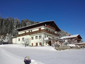 Un edificio nella neve con un bambino davanti di Gästehaus Hauser a Bach