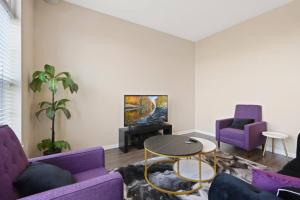 a living room with purple couches and a tv at Private Bed Downtown INDY - Shared in Indianapolis