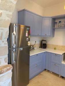 a kitchen with blue cabinets and a stainless steel refrigerator at Villa Laugh, on The Limnes Beach in Kampos Paros