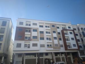 a tall white building in front of two buildings at home Lesieur in El Jadida