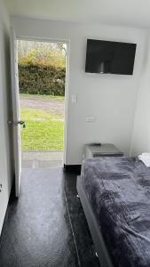 1 dormitorio con 1 cama y puerta corredera de cristal en Hostal Vallegrande en Rionegro