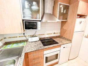 małą kuchnię z kuchenką i lodówką w obiekcie Jardines al Mar piscina y garaje w mieście Oropesa del Mar +16 zdjęć