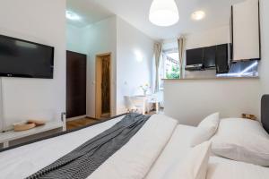 a bedroom with a large white bed with a flat screen tv at Rooms Eden Old Town in Dubrovnik