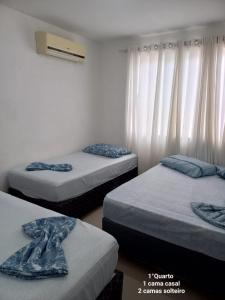 three beds in a room with white curtains at Casa em Itajaí Balneário Camboriú e Parque Beto Carrero in Itajaí